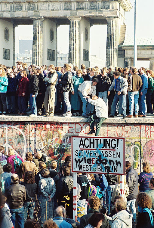 People atop the Berlin Wall near the Brandenburg Gate on 09 November 1989