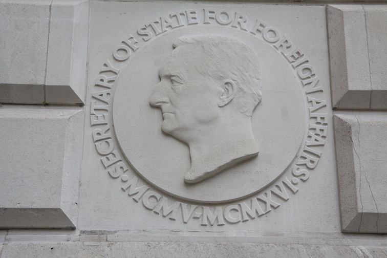 A silhouette face on a stone carving, around it there is text: Secretary of Foreign Affairs