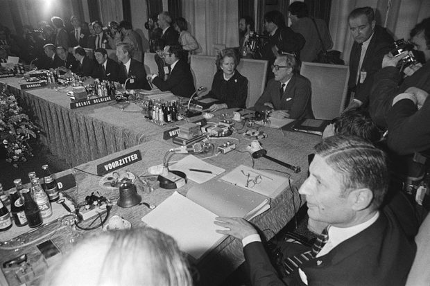 A group of people sat around a table, placed at their assigned places including Thatcher and Carrington