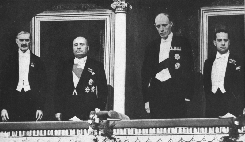 4 men at the opera looking down from a balcony, left to right is Neville Chamberlain, Benito Mussolini, Lord Halifax, and Count Ciano