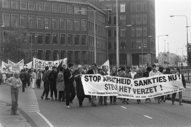 A demonstration march. people are holding a banner saying stop the apartheid